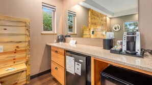 A modern kitchen with a built-in dishwasher, a coffee maker, and wooden cabinetry. - ADA King Room, AC, Fireplace, hot tub - Lodge 103 (Estes Park)