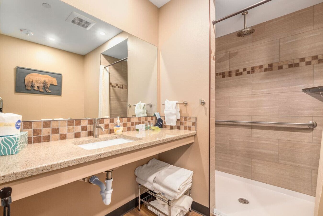 A bathroom with a sink, mirror, towel rack, and shower.