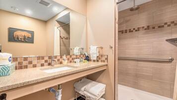A bathroom with a sink, mirror, towel rack, and shower.