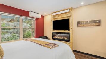 A bedroom with a large bed, a TV, and a fireplace.