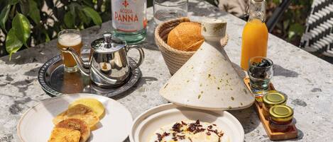 A table set with breakfast items including toast, eggs, and condiments, with a bottle of Acqua Panna water and a basket of bread.