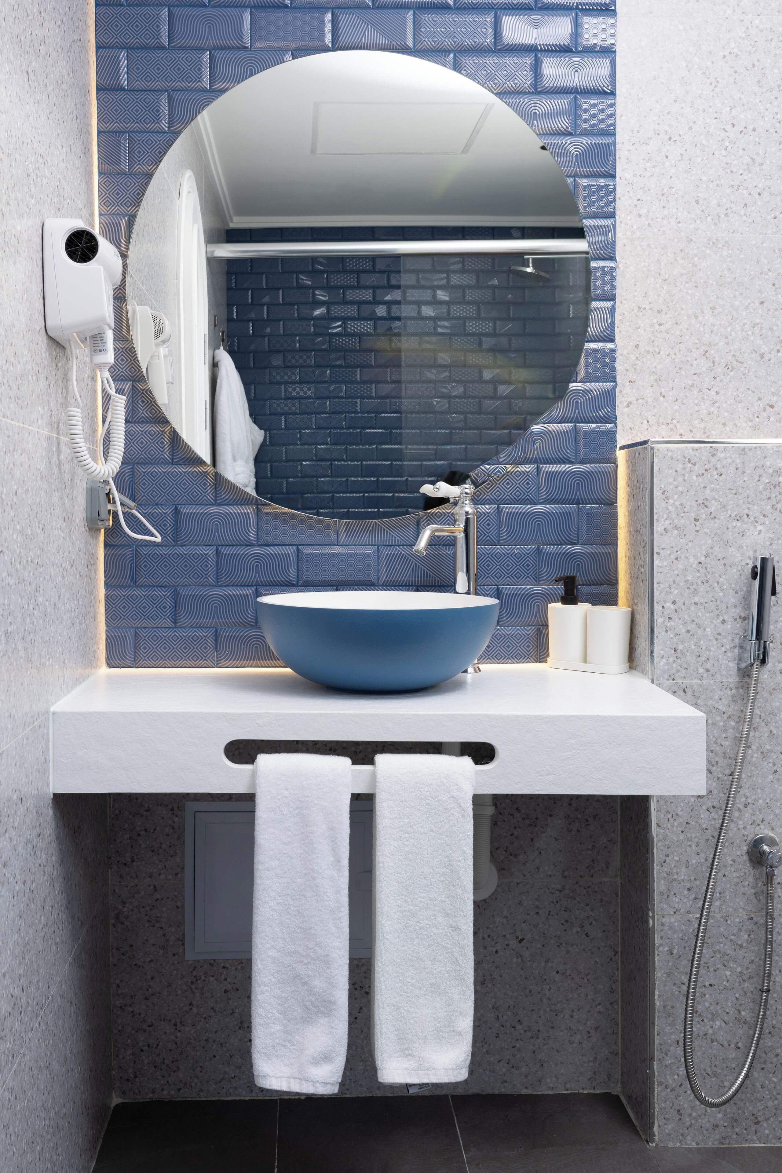 A bathroom with a blue sink, a large mirror, a towel rack, and a shower.