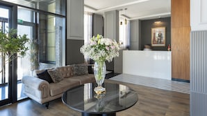 A modern lobby with a glass coffee table, a sofa, and a reception desk. - Aurea Hotel (Tetouan)