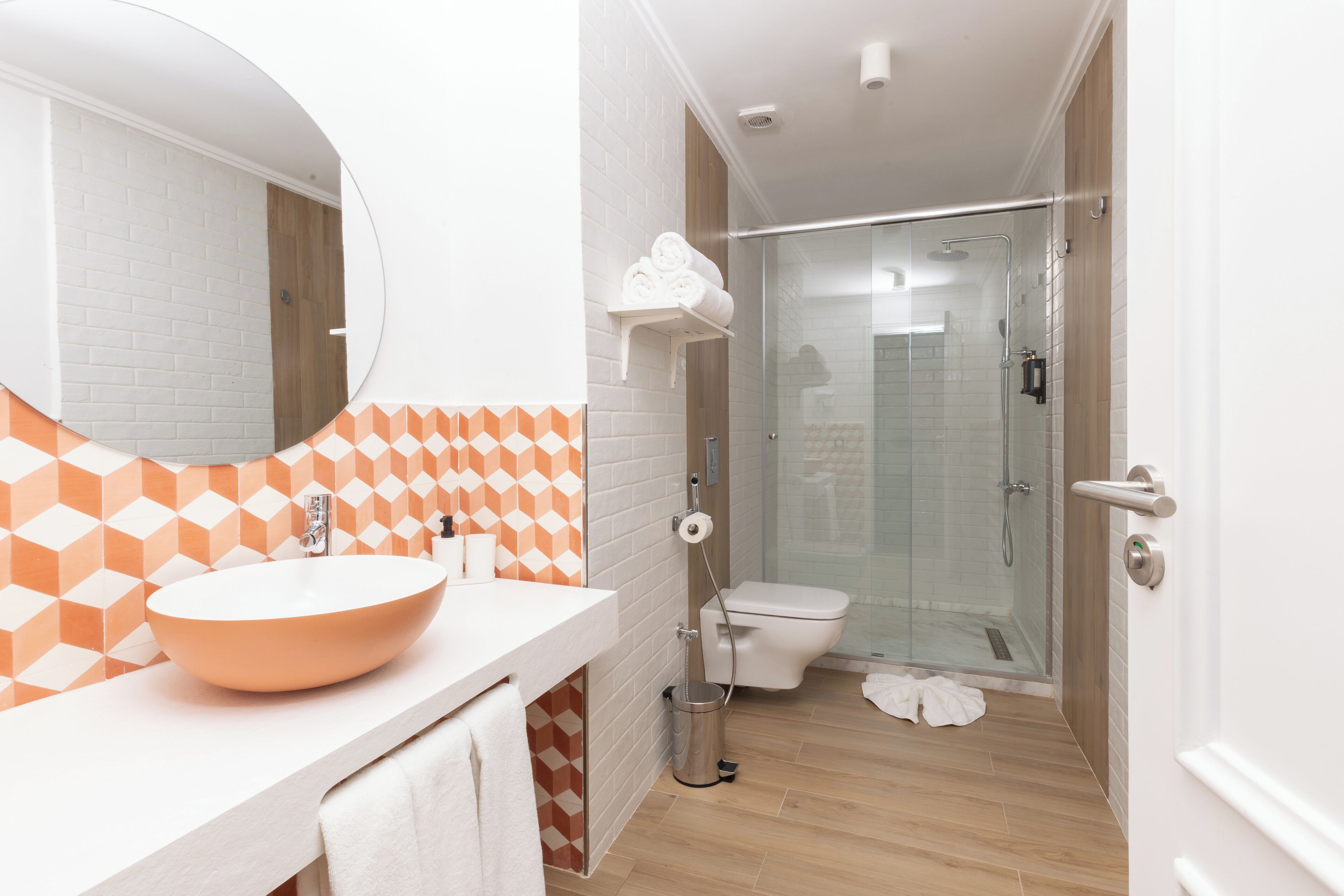Un baño moderno con un lavamanos ovalado grande, un inodoro y una ducha con cerramiento de vidrio.