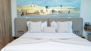 A hotel room with a large bed, two bedside tables, and a painting of a historical building on the wall.