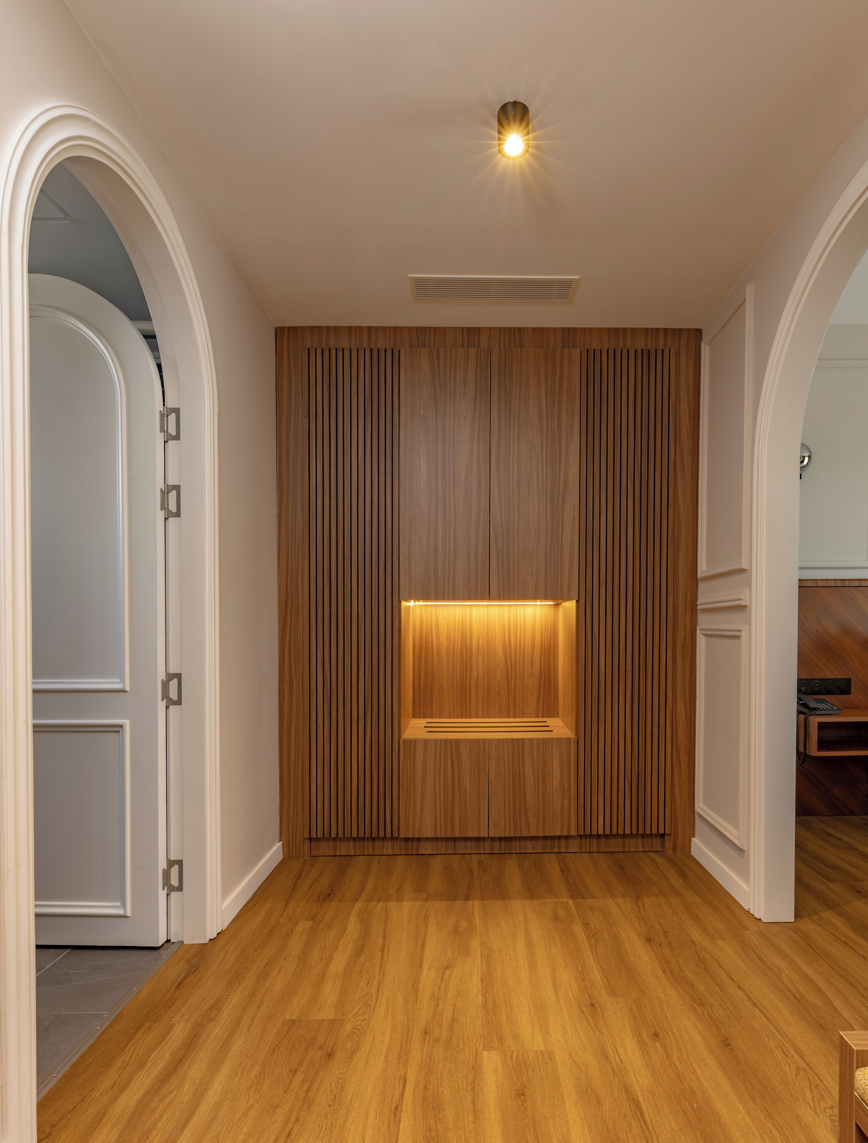 A modern room with wooden paneling, a built-in TV, and a ceiling light.