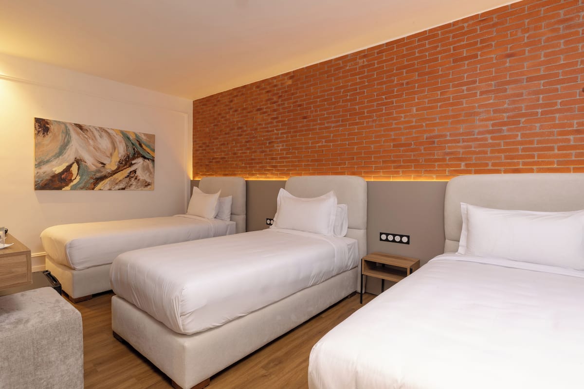 Habitación de hotel con dos camas, una pared decorada con ladrillos y un cuadro en la pared.