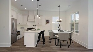 A modern kitchen with white cabinetry, a central island, and pendant lighting.