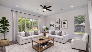 A modern living room with a white sofa set, a wooden coffee table, and a ceiling fan.