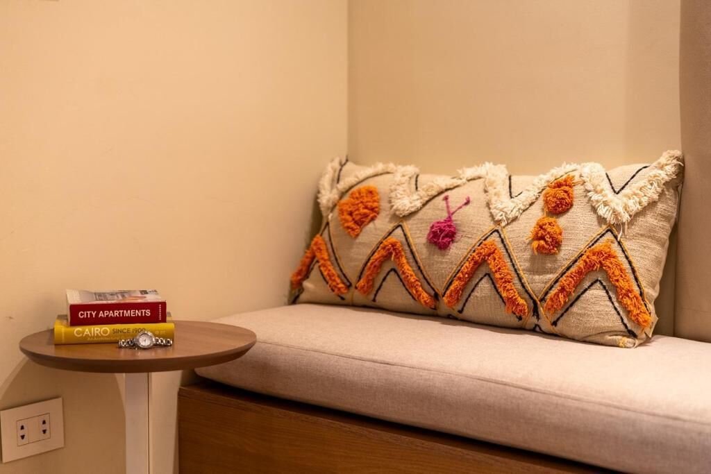 A sofa with a decorative pillow featuring a zigzag pattern and tassels.