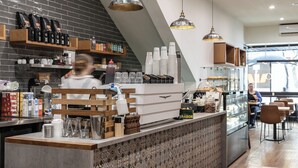 Interior de cafeteria moderna amb un mostrador, prestatges amb grans de cafè i una persona al fons.