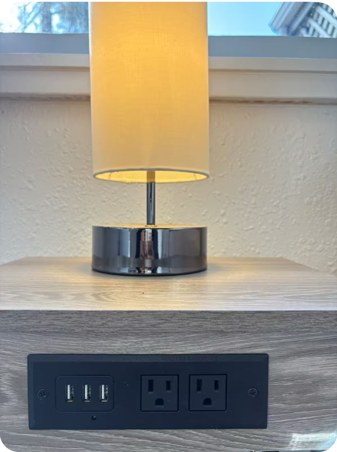 A lamp on a wooden surface with a power strip below it.