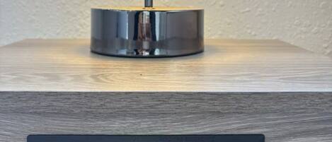 A lamp on a wooden surface with a power strip below it.
