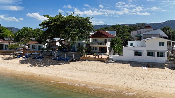 Une propriété située en bord de mer, dotée d’une piscine, de chaises longues et offrant une vue sur l’océan.