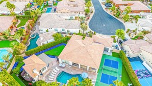 A residential area with multiple houses, a winding road, and a large swimming pool with a tennis court. - 0.4 Acre- Indio Sapphire Oasis with Game Room (Indio)
