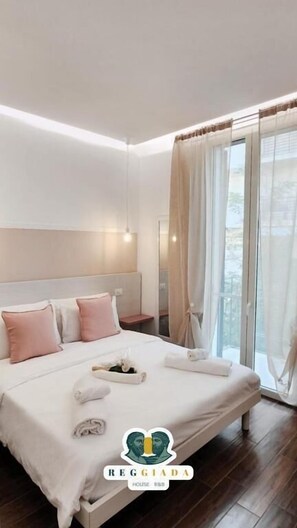A modern hotel room with a large bed, a nightstand, and a window with curtains. - RegGiada house (Reggio Calabria)