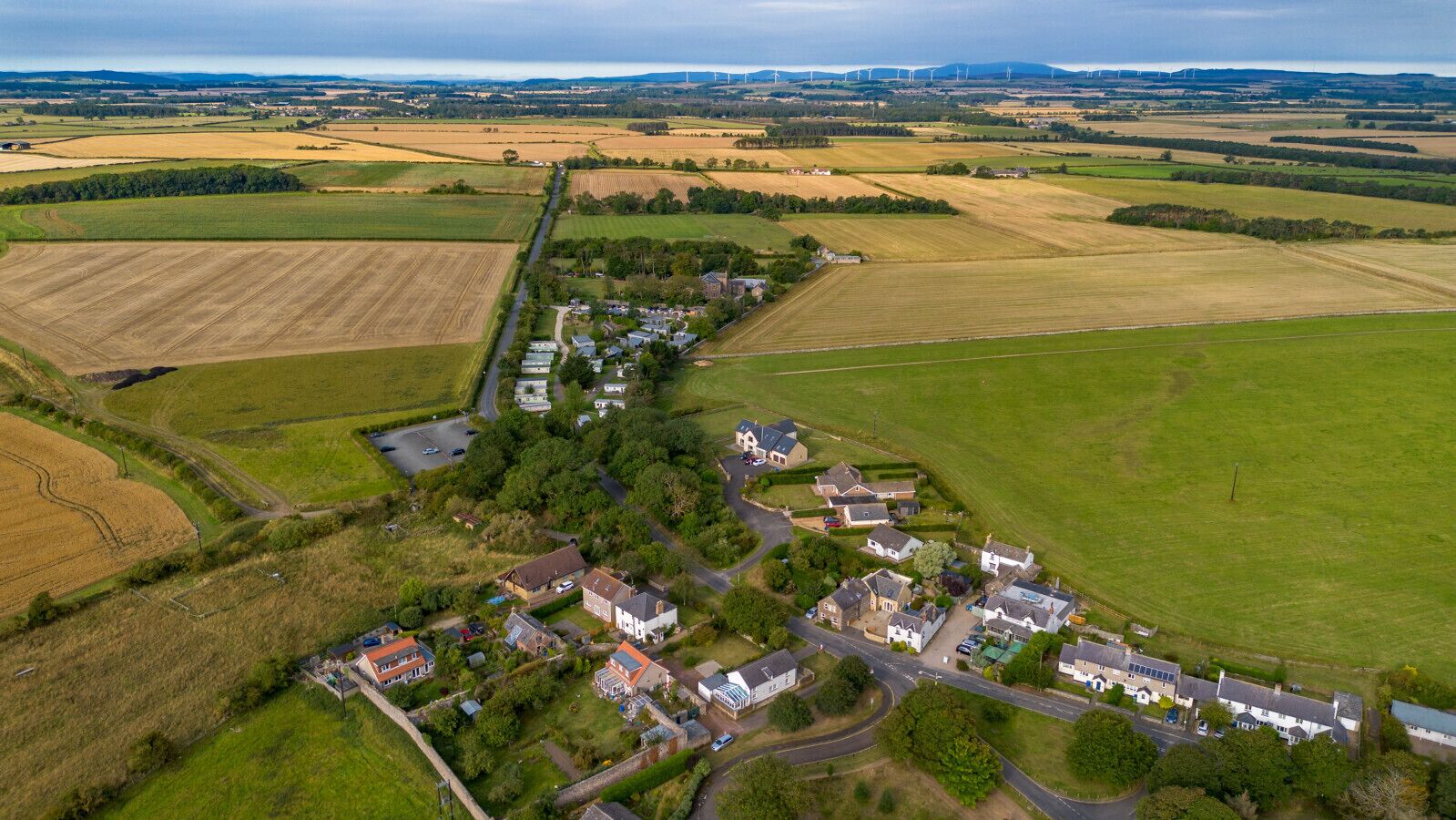 An aerial view of a rural village with houses, roads, and fields.