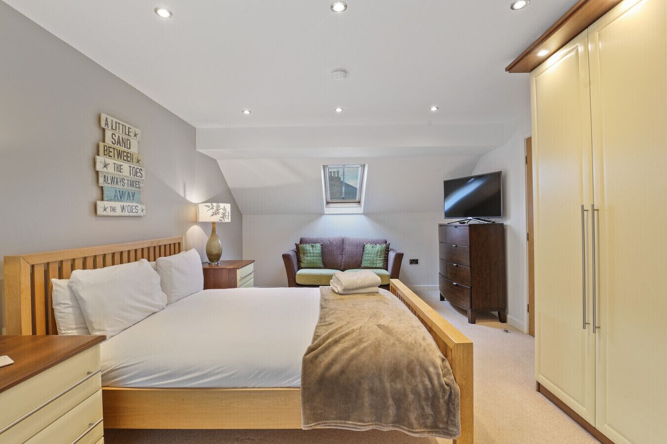 A bedroom with a large bed, a TV, a wardrobe, and a ceiling light.