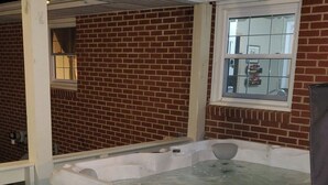 A hot tub in a room with brick walls and a window.