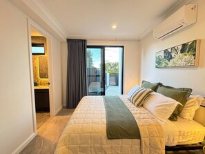 A bedroom with a bed, a window, and a door leading to a balcony.