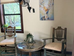 A room with two wooden chairs, a glass table, a potted plant, and a painting of a deer. - Two six-bedroom Guest Houses with shared kitchen, dining area, living room area (Mason County)