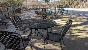 A patio area with a round metal table and chairs, a pool, and a fenced garden.