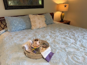 Una cama bien hecha con un adorno decorativo, un cuadro en la pared y una lámpara en la mesita de noche.