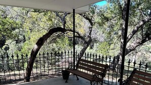 A covered outdoor area with a concrete floor, two wooden benches, and a metal fence. - Legacy Ranch-Family Reunion Facility. Four Guest Houses, Recreation Center, & Swimming Pool (Mason)