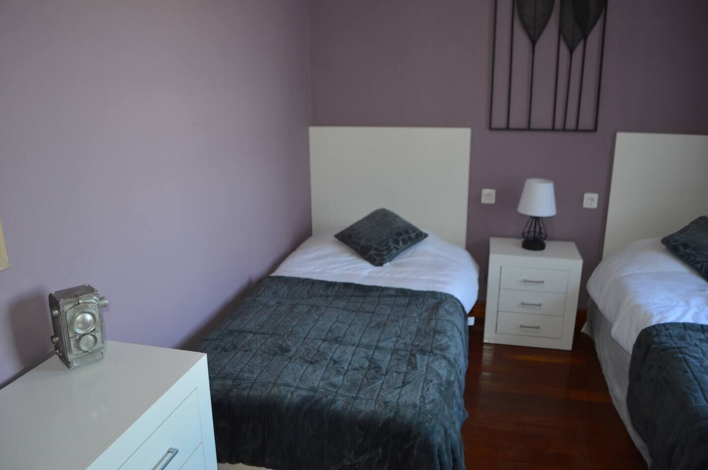 Un dormitorio con dos camas, un aparador, una lámpara y un altavoz.