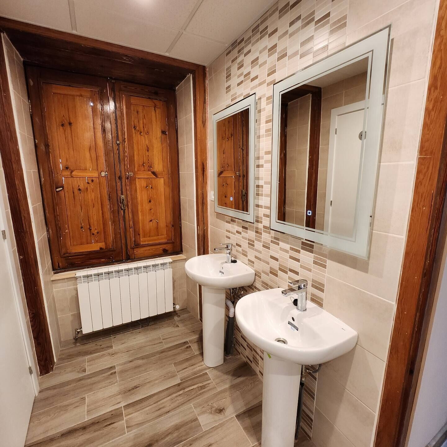 Ein Badezimmer mit Holzschränken, zwei Waschbecken und einem Spiegel.