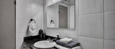 Un bagno moderno con uno specchio grande, un lavabo e un porta asciugamani.