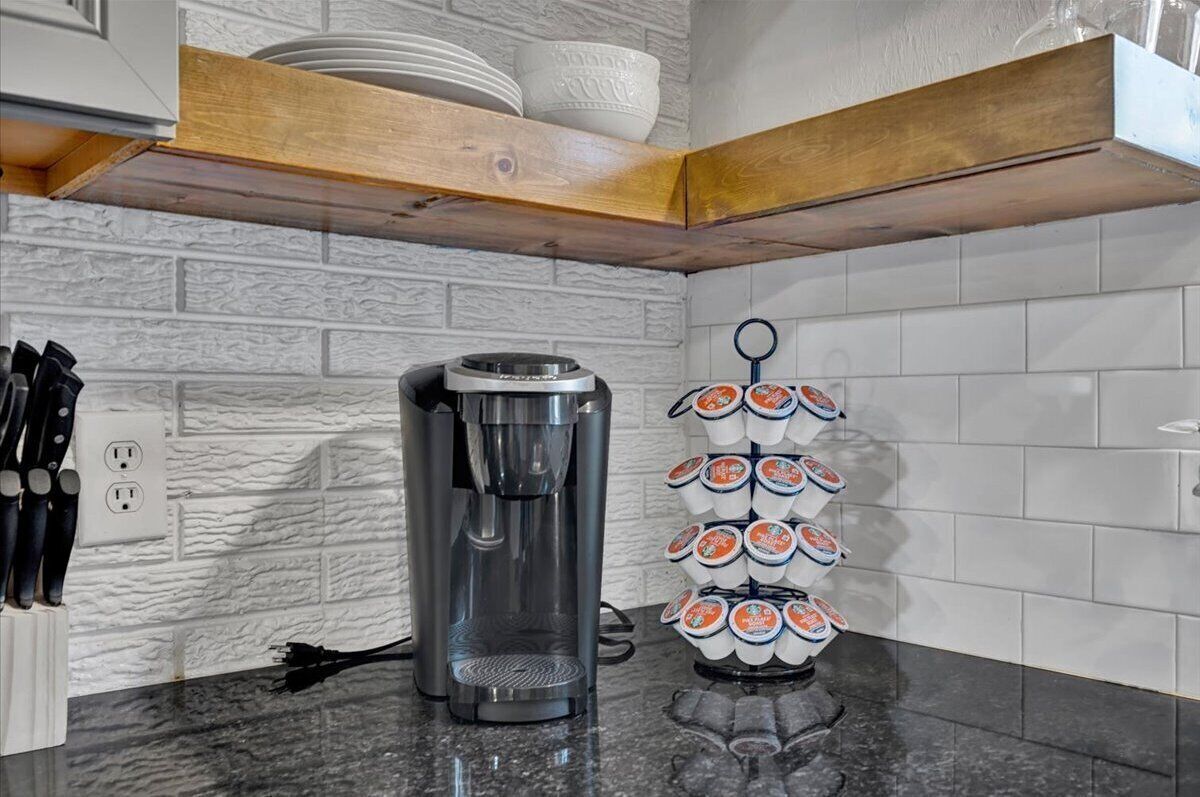 A kitchen with a coffee maker, a knife block, and a mug rack.