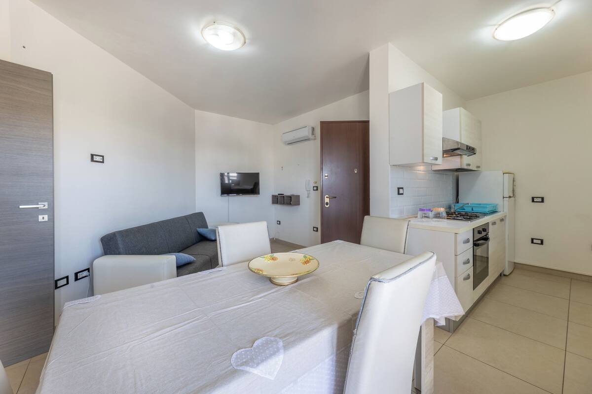 A compact living space with a dining area, kitchenette, and a sofa in the background.