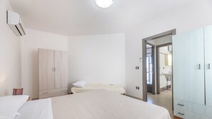 Une chambre à coucher avec un lit, une armoire et une salle de bain visible à travers une porte ouverte.
