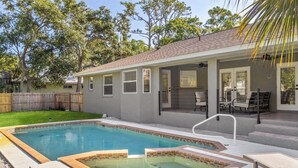 A backyard with a swimming pool, a covered patio with outdoor furniture, and a wooden fence. - Chic happens 3/2 heated pool 5 min from Siesta (Sarasota)