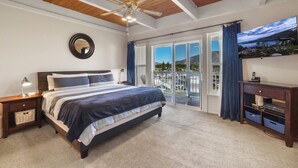 Une chambre à coucher avec un lit, un ventilateur de plafond, une télévision et un balcon offrant une vue panoramique.