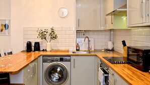 A compact kitchen with a built-in washer, a microwave, and a sink. - Pass the Keys | Llandaff - Modern, Bright & Central w/Parking (Cardiff)