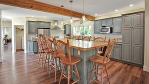 A spacious kitchen with a central island, wooden chairs, and modern appliances. - The Farmhouse at Pine Creek (Watson Township)