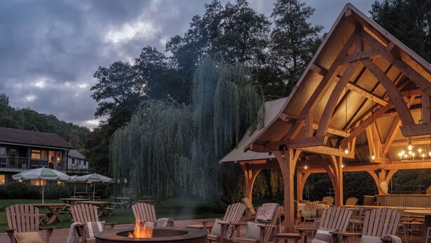 A wooden pavilion with outdoor seating, a fire pit, and a view of a waterfall. - The Royal George (Tintern)