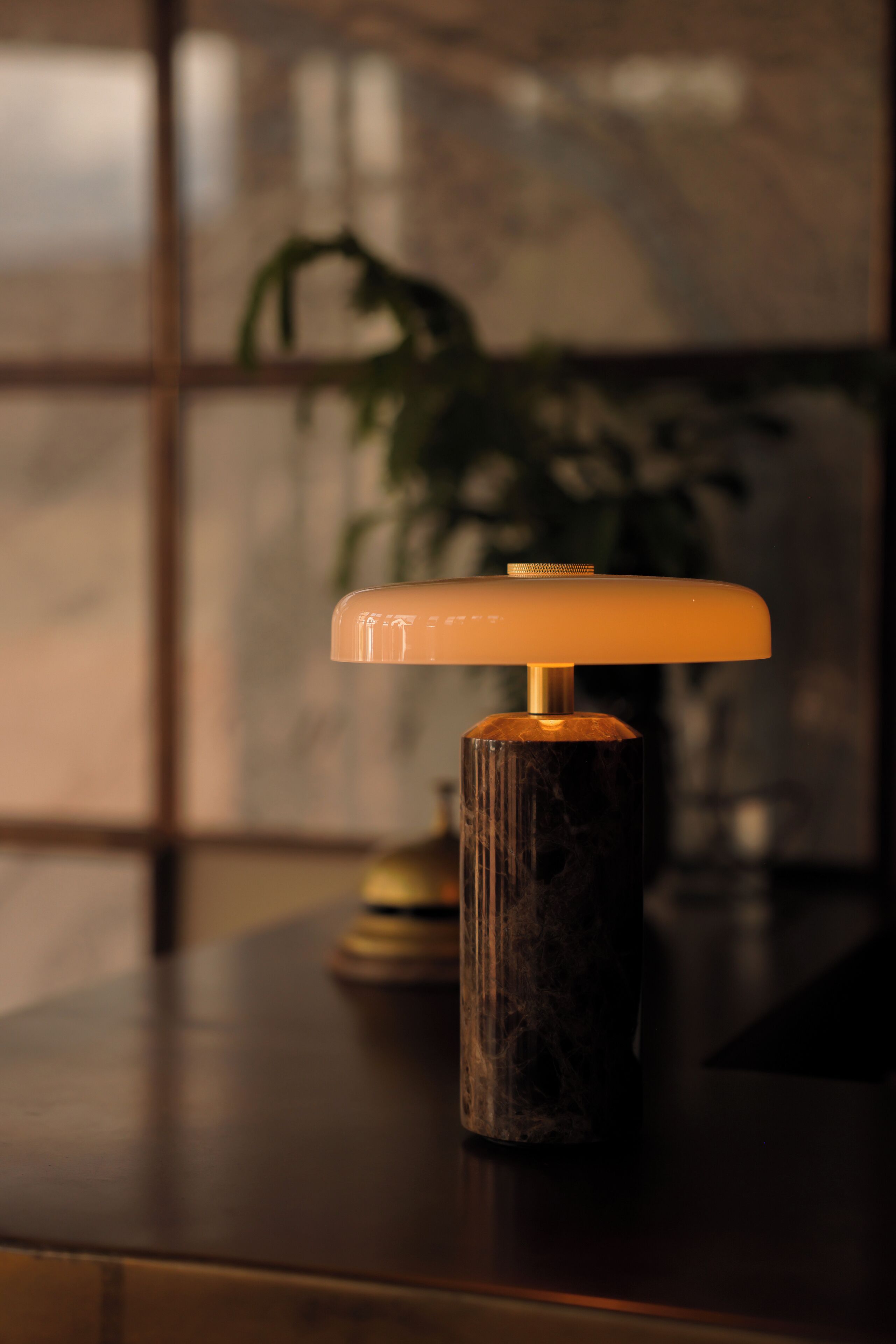A table lamp with a cylindrical base and a flat, illuminated top, placed on a wooden surface.