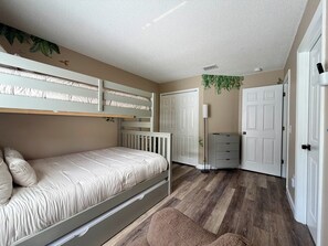 A room with a bunk bed, a desk, a chair, a wardrobe, and a door. - Cozy Palms Villa: 4BR, 3BA Home, South-Facing Pool & Spa – Mins to Disney! (Davenport)