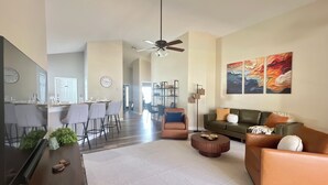 A modern living room with a sofa, coffee table, and a dining area with chairs and a table. - 4BR Private Pool & Spa | Game Room | 35 Min to Disney (Davenport)