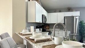 A modern kitchen with white cabinets, a stainless steel refrigerator, and a granite countertop.
