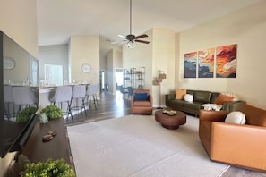 A modern living room with a sofa, coffee table, and a dining area with chairs and a table.