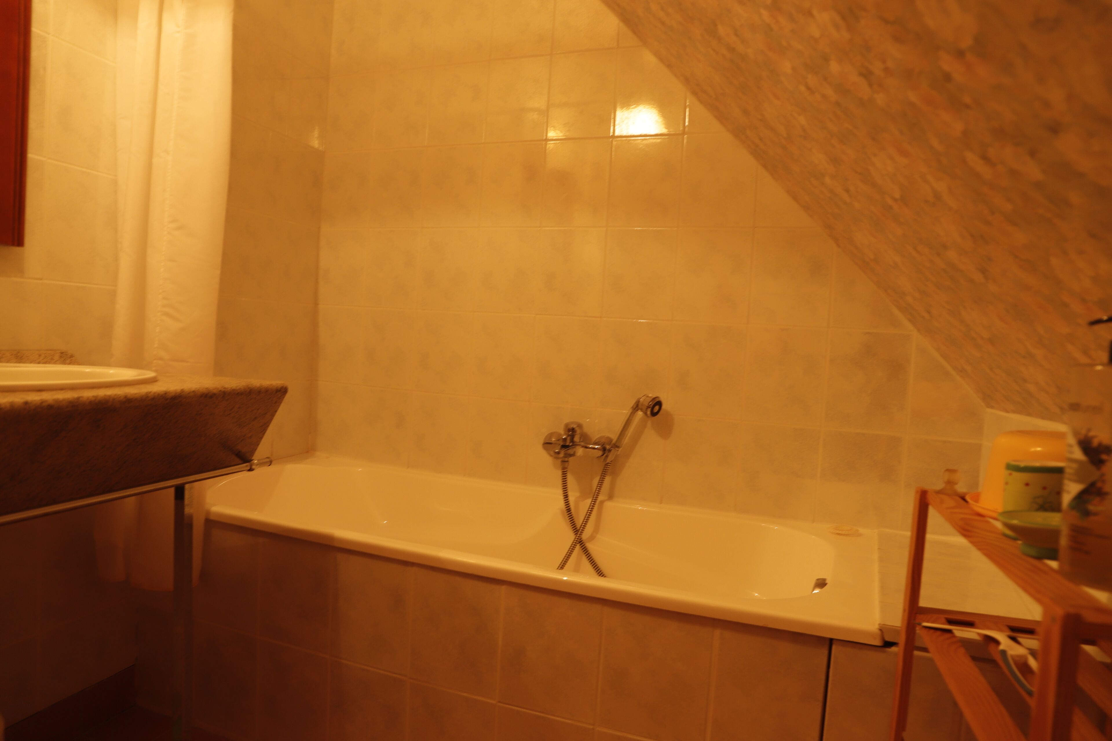 Une salle de bain avec une baignoire, une chaise en bois et un lavabo.