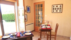 A dining area with a table set for two, a wooden chair, and a door leading outside. - Country home in the heart of France, 20 minutes away from Sancerre (Assigny)
