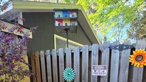 A patio with two chairs and a table, a wooden fence, and a birdhouse. - Edith - Glamping in Springs Country. Walk to downtown High Springs! (High Springs)