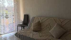 A modern living room with a sofa, a chair, and a large window with sheer curtains. - House Swap Frejus (Frejus)