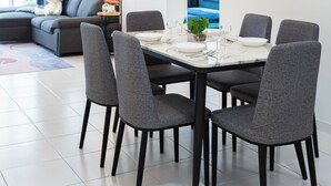 A modern dining area with a round table, six grey chairs, and a ceiling fan. - Pool View 3BR* Walk to SHOPS EAT * AC & Wi-Fi (Tanjung Tokong)