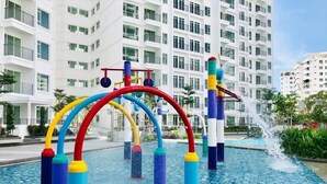 A water play area with colorful structures in front of a modern hotel building. - Pool View 3BR* Walk to SHOPS EAT * AC & Wi-Fi (Tanjung Tokong)